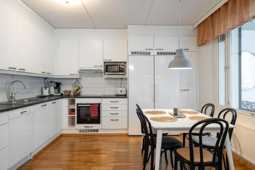 拉赫蒂Kokonainen huoneisto 73m2 keskeisellä sijainnilla, ilmainen parkkipaikka的厨房配有白色橱柜和桌椅