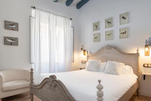 塞维利亚Magno Apartments Vírgenes Luxury House的卧室配有白色的床和椅子