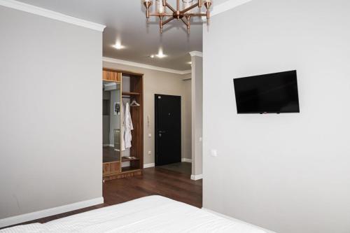 阿拉木图Deluxe Park Z hotel的卧室设有白色墙壁和平面电视。