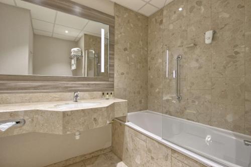 朗吉斯假日度假奥利酒店的一间带水槽、浴缸和镜子的浴室