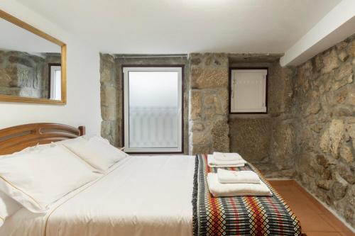 戈韦阿Rustic Getaway in Guarda的一间卧室设有一张床和石墙