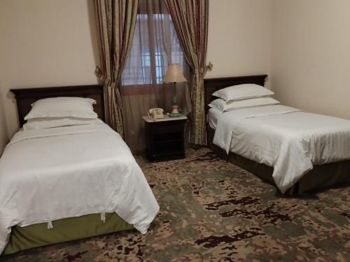 吉达فندق روتانة الحمراء的一间卧室设有两张床、一张桌子和一个窗口