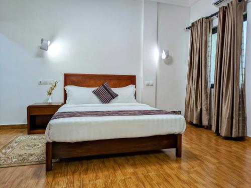 科托努Les Ombrelles Appart'Hotel的一间卧室配有一张大床和木制床头板