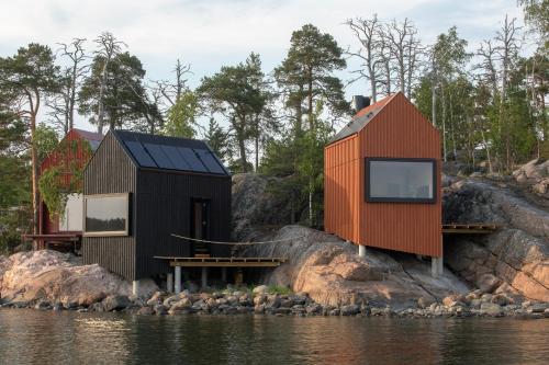 赫尔辛基Majamaja Helsinki off-grid retreat的水体岸边的两座房子