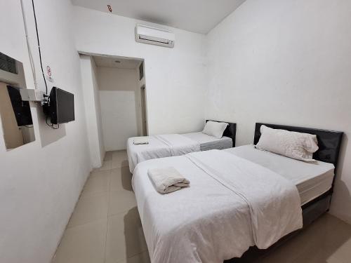 巴东Tanjung Syariah的白色墙壁客房的两张床