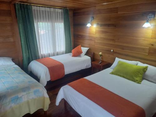 PaloraFinca La Esperanza的木墙客房的两张床