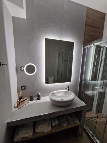 沃洛斯Volos Suites Center的一间带水槽、镜子和淋浴的浴室