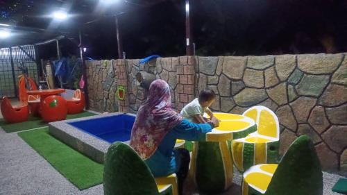 哥打巴鲁Airport Kota Bharu Homestay & Riverview Inn的一名女子和一个儿童在操场上玩耍