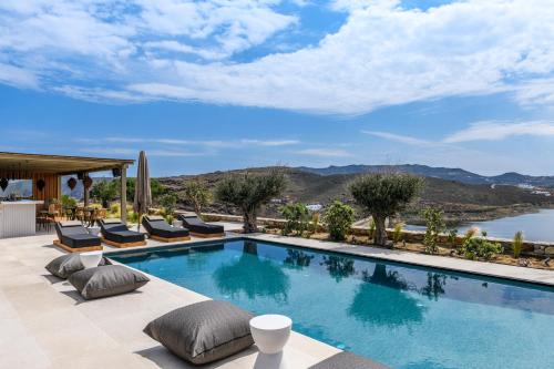 帕诺尔莫斯米科诺斯Panormos Bay Suites Luxury Resort的一个带椅子的游泳池,享有水景