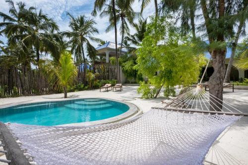 布韦朱RoRi Private Luxury Villas的一个带游泳池和棕榈树的庭院内的吊床