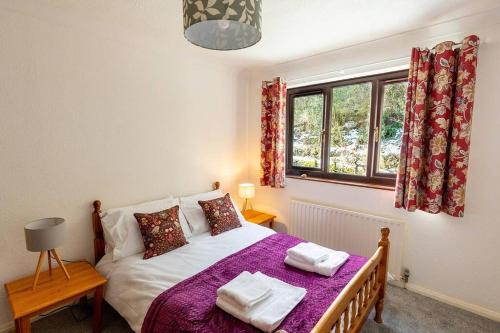 肯德尔UNDERWOOD COTTAGE - Peaceful House in Kendal with views of Cumbria的一间卧室配有一张带紫色床单的床和窗户。