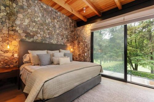 El PedregalHermosa Casa frente a campo de golf的一间卧室设有一张大床和石墙