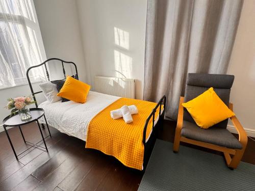 伦敦Acacia Flat 189 in Wembley的一间卧室配有一张带黄色枕头和椅子的床