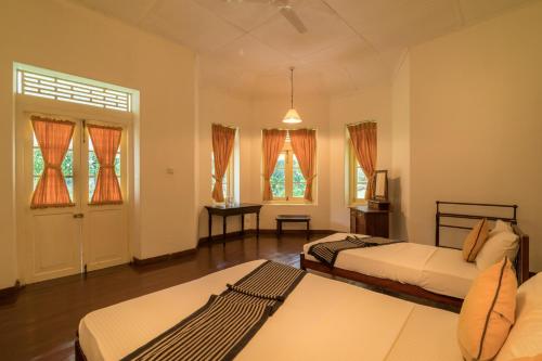 DeraniyagalaUdapola Bungalow的一间带两张床的卧室和一间带窗户的房间
