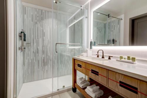 休斯顿休斯敦大学希尔顿酒店的一间带玻璃淋浴和水槽的浴室