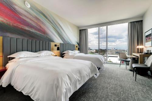 休斯顿休斯敦大学希尔顿酒店的酒店客房设有三张床和大窗户