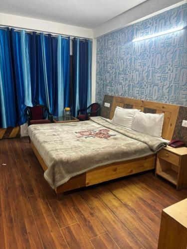 西姆拉Asha Residency Shimla - Airport Road的一间卧室配有一张带蓝色窗帘的大床