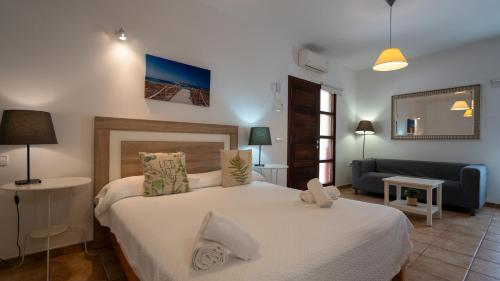 圣费兰-德瑟斯罗Apartaments ES POU的卧室配有一张白色的大床和一张沙发。