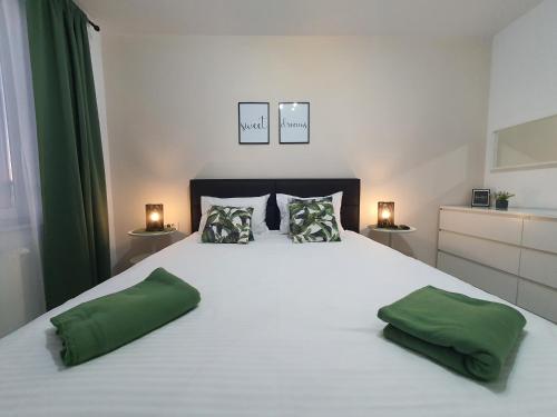布拉索夫GREEN Apartment Coresi的卧室配有一张带两个绿色枕头的大型白色床