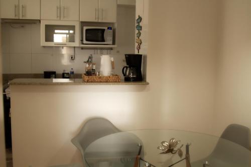 贝洛奥里藏特Apartamento Gutierrez 2的厨房配有玻璃桌和微波炉