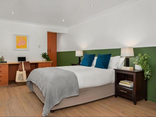 开普敦Neighbourgood Ravenscraig的一间卧室设有一张大床,拥有蓝色和绿色的墙壁