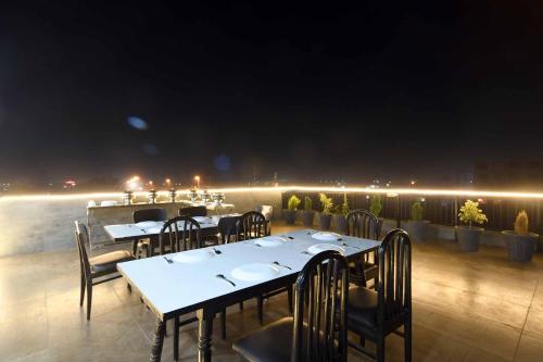 印多尔Aceotel Select Tulsi Vijay Nagar的晚上在阳台上设有桌椅的餐厅