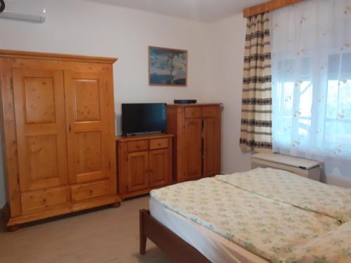 扎马迪Balaton 116的一间卧室配有一张床、一台电视和木制橱柜。