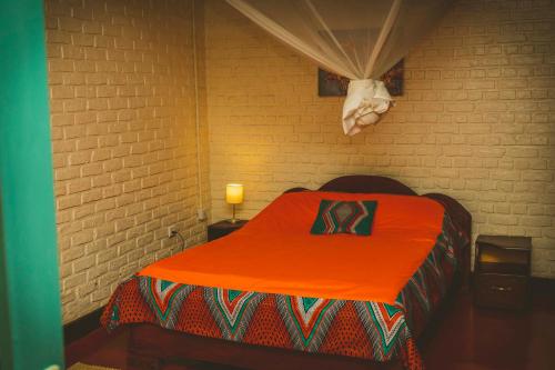 RuhengeriRoom in Guest room - Isange Paradise Resort的配有橙色毯子的床的房间