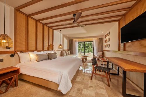 艾库玛尔Bahia Principe Luxury Akumal - All Inclusive的一间卧室配有一张床、一张书桌和一台电视