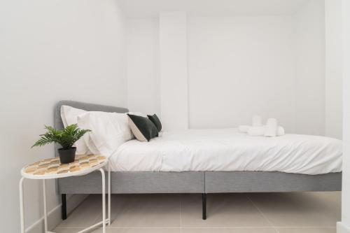 马拉加Suite Homes Hesperides 914的一张铺有白色床单的床,上面有植物