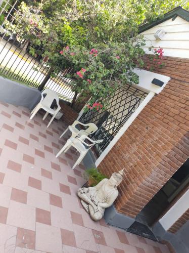 洛马斯-德萨莫拉Dakini Hostel的庭院配有两把白色椅子和雕像