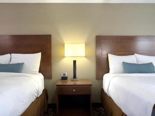 格林斯堡Super 8 by Wyndham Greensburg的酒店客房设有两张床和一张带台灯的桌子。