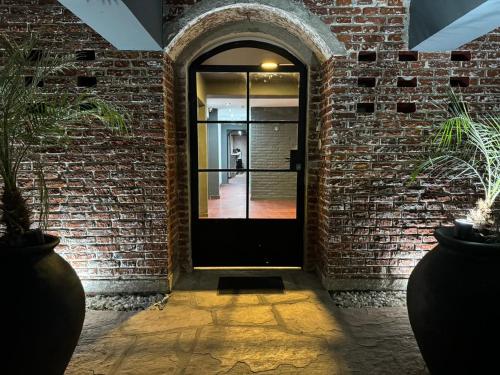 维拉卡洛斯帕兹Nuevo Hotel Ciervo de Oro- By HVH的砖墙中一扇有植物的黑色门
