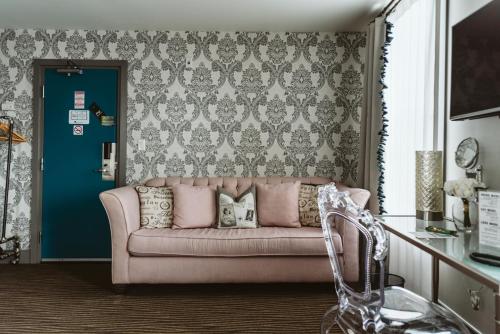 KingsvilleThe Grove Hotel的客厅里设有一张粉红色的沙发,客厅里设有蓝色的门