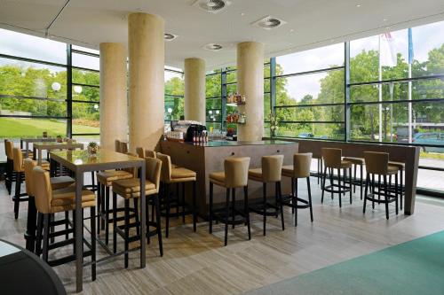 波恩波恩万豪酒店的餐厅设有桌椅和大窗户。