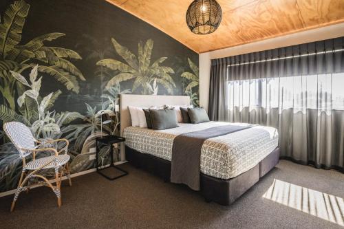 奥霍普海滩Ohope Beach TOP 10 Holiday Park的一间卧室配有一张带热带壁纸的大床
