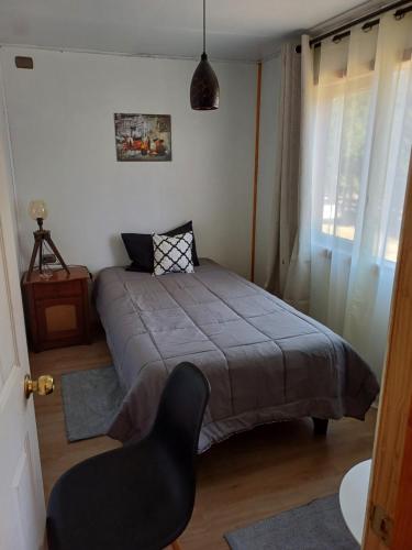 瓦尔迪维亚CABAÑAS LOMAS DE YECO的一间卧室配有一张床和一把椅子