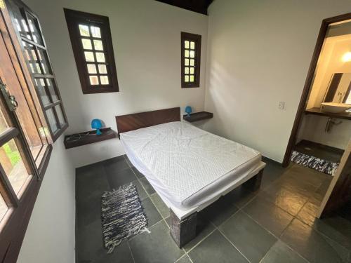 坎布里Camburi Chalés的卧室位于客房的角落,配有一张床