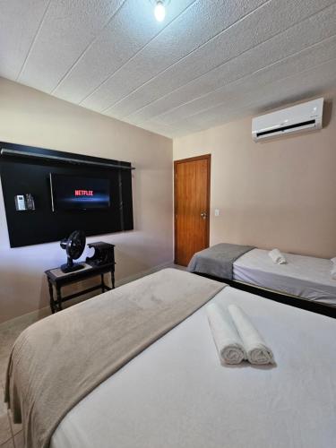卡马萨里Arembepe - Aldeia St Sebastien Casa Mar 10的一间卧室设有两张床,墙上配有电视。