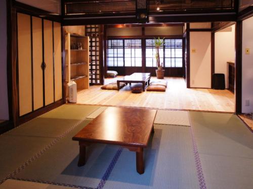 Yokota（一棟貸切）町家体験ゲストハウス「ほんまちの家」〜高岡市の伝統的な古民家～的客厅配有一张木桌,位于地板上