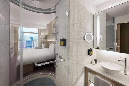 香港Lodgewood by Nina Hospitality Mong Kok的浴室设有床、水槽和镜子
