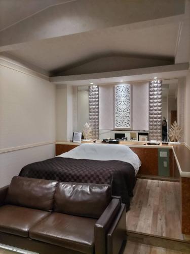Kurihashiホテル ウォーターバリ栗橋的一间卧室配有一张大床和一张皮沙发