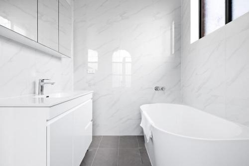 班克斯镇Cozy Bankstown Stayz的白色的浴室设有浴缸和水槽。