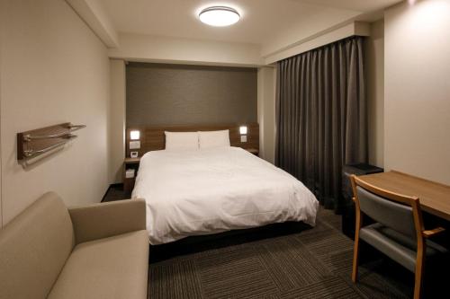 丰桥市Dormy Inn Express Toyohashi的配有一张床和一张书桌的酒店客房