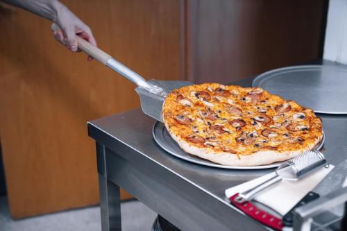 米湖沃加尔旅行服务旅馆的一个人用西班牙 ⁇ 刀剪披萨