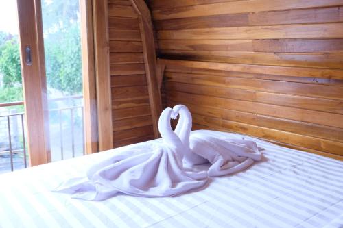 珀尼达岛Garuda Hostel & Accomodation Nusa Penida的坐在床上的白色天鹅