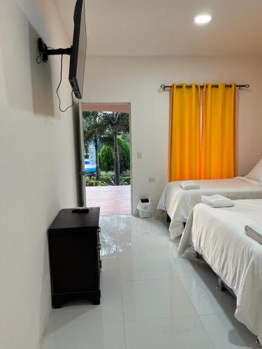 莫约加尔帕Hotel Campestre Bella Vista Ometepe的一间卧室配有两张床和橙色窗帘