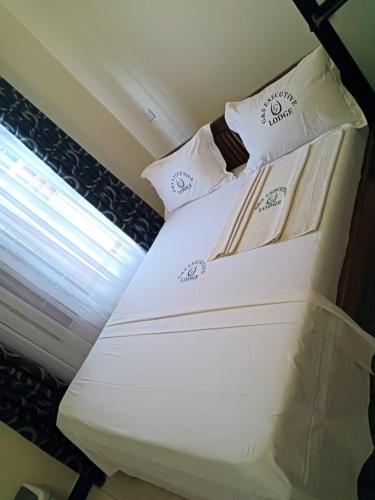 达累斯萨拉姆G & S Executive Lodge的窗户客房内的一张白色床