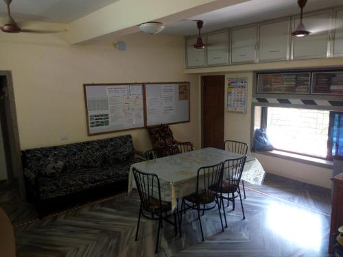 BhogweGovindaashram的一间带桌椅和沙发的用餐室