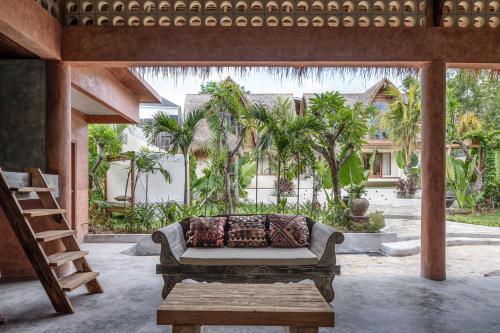 乌鲁瓦图Lulu's Villas的天井配有沙发和桌子,种有棕榈树